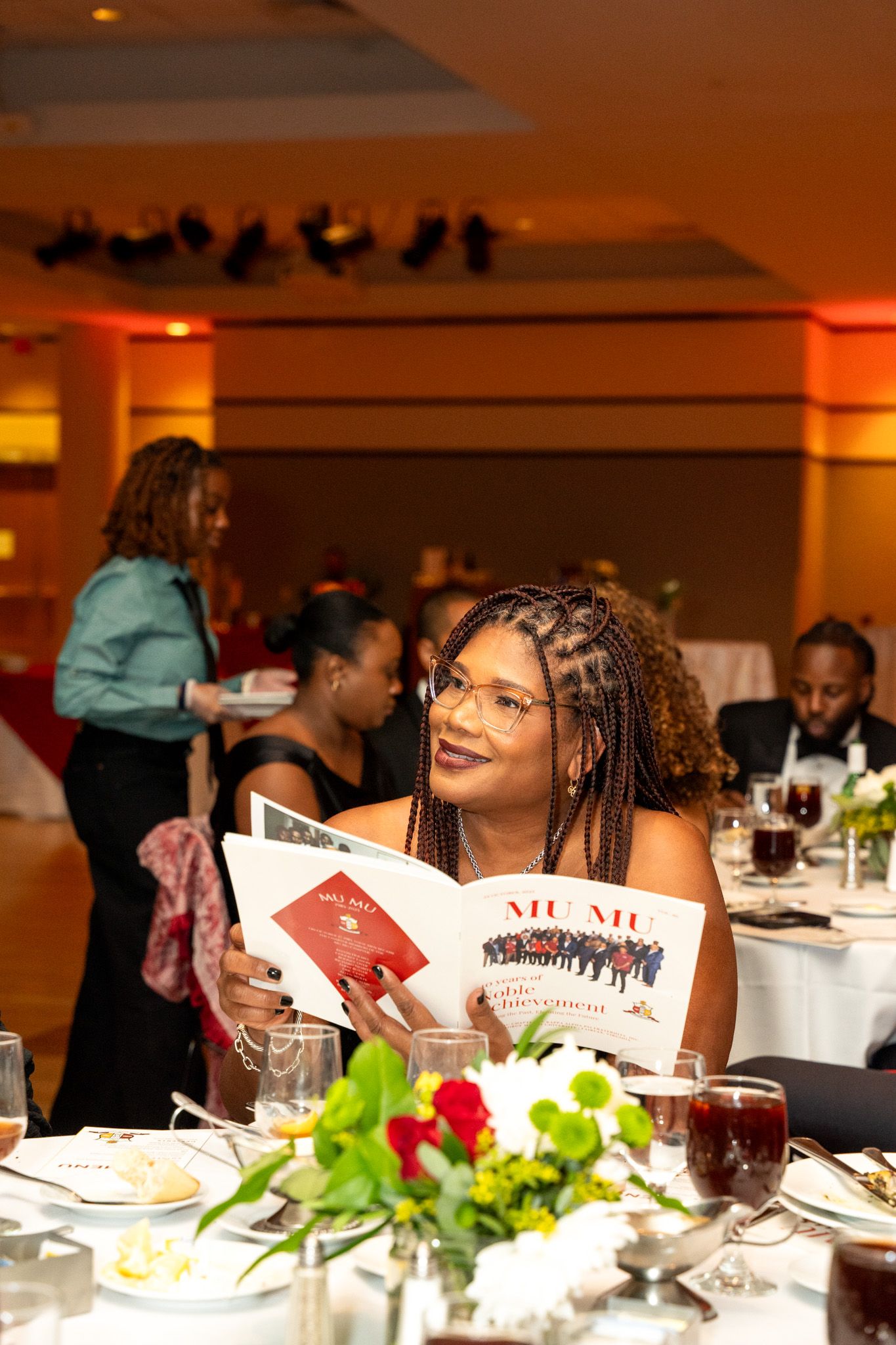 Guests seated at elegantly decorated dinner tables with floral centerpieces.