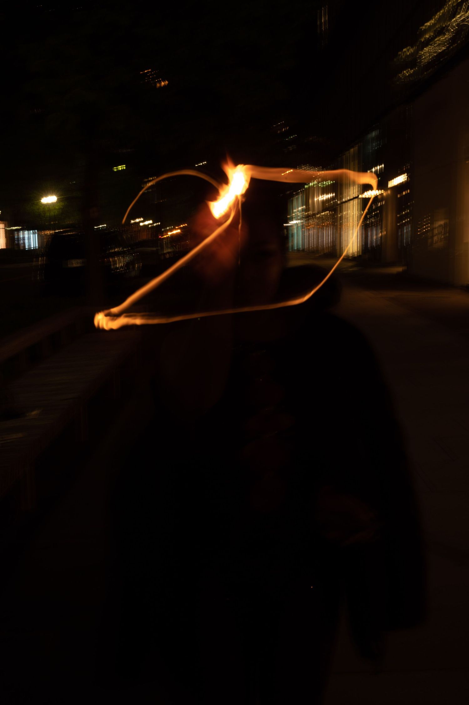 Long exposure photo shows glowing light trails creating abstract patterns against dark background at night.