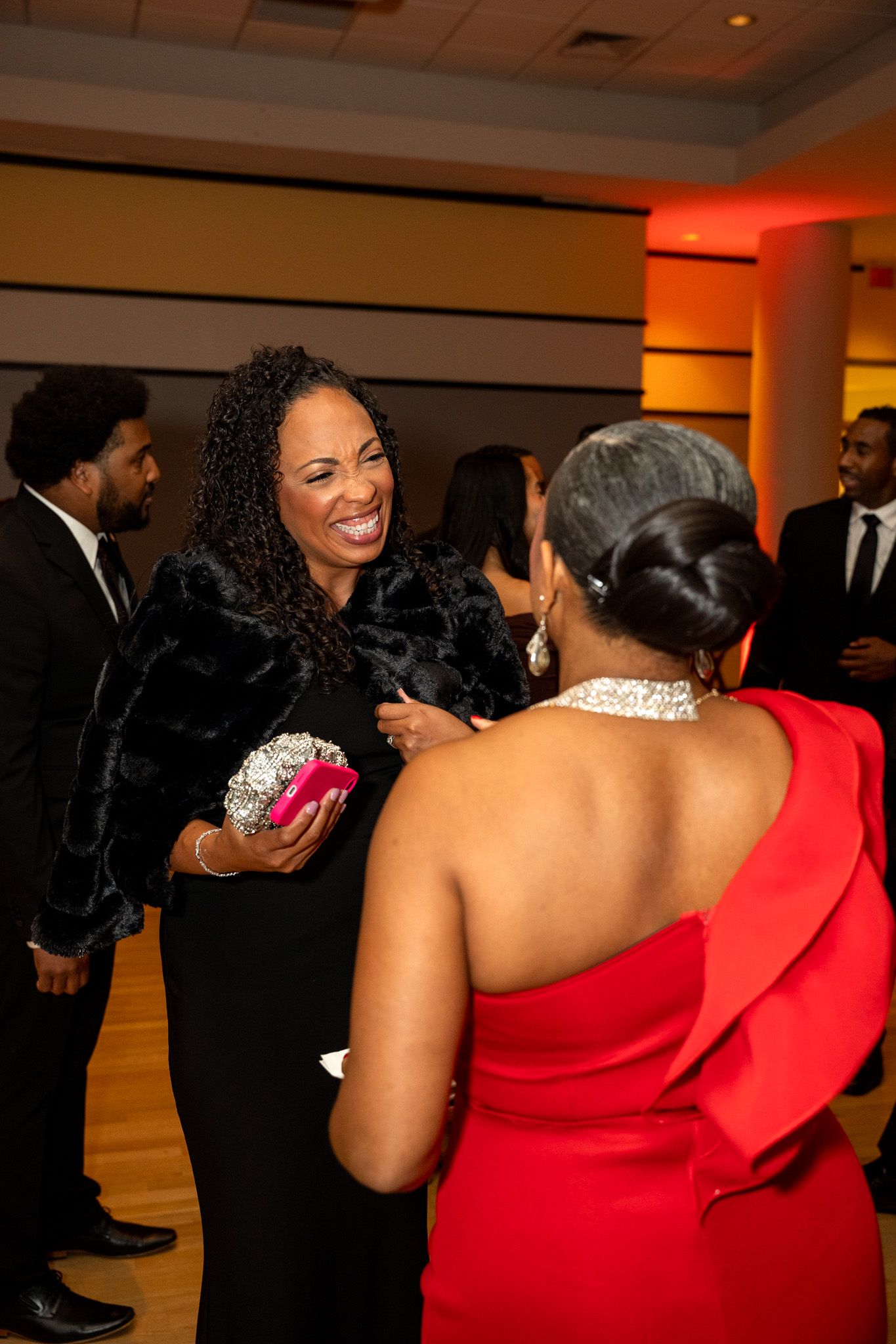 Guests sharing a joyful moment at formal event, wearing elegant evening attire.