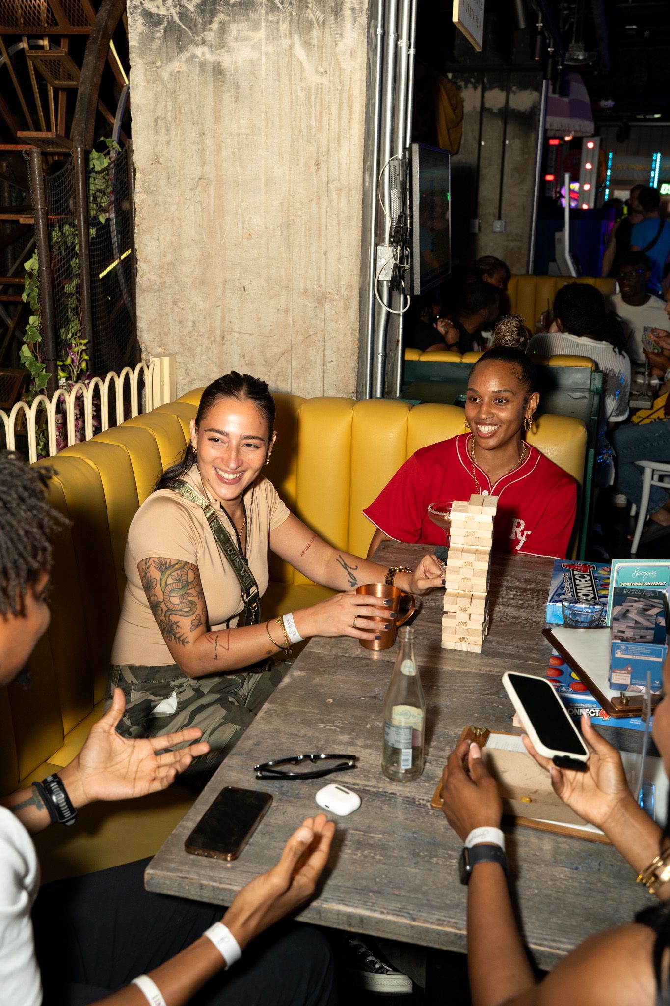 Group enjoying drinks and conversation at a table in a dimly lit venue.