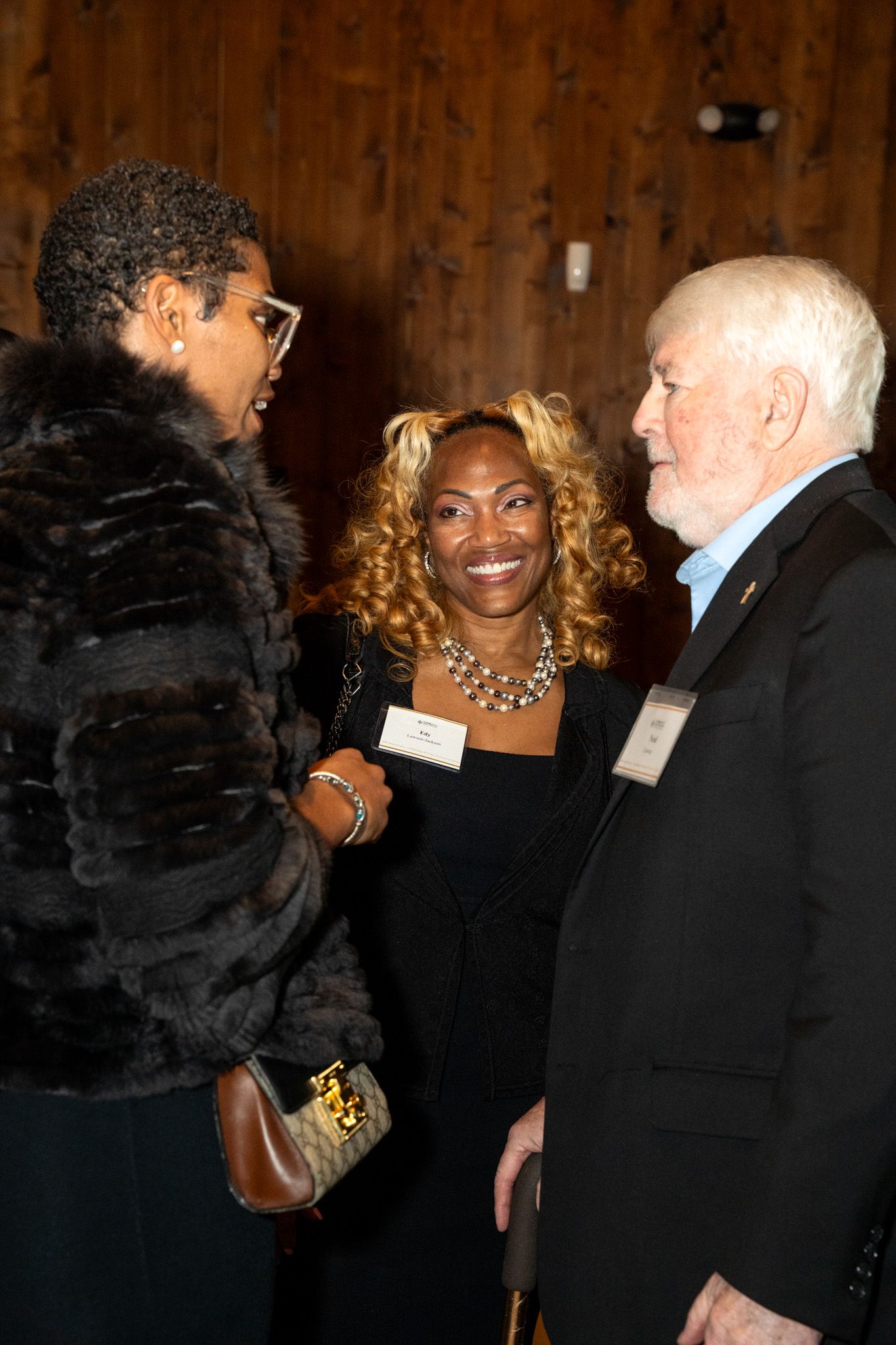 Attendees in formal attire interact during what appears to be an evening networking event.