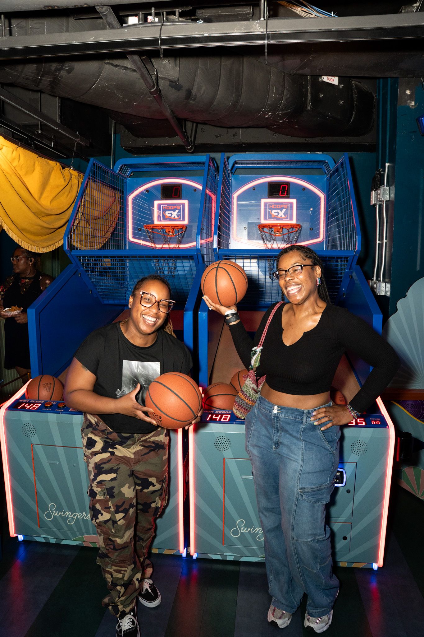 Friends playing basketball arcade games in an entertainment venue.