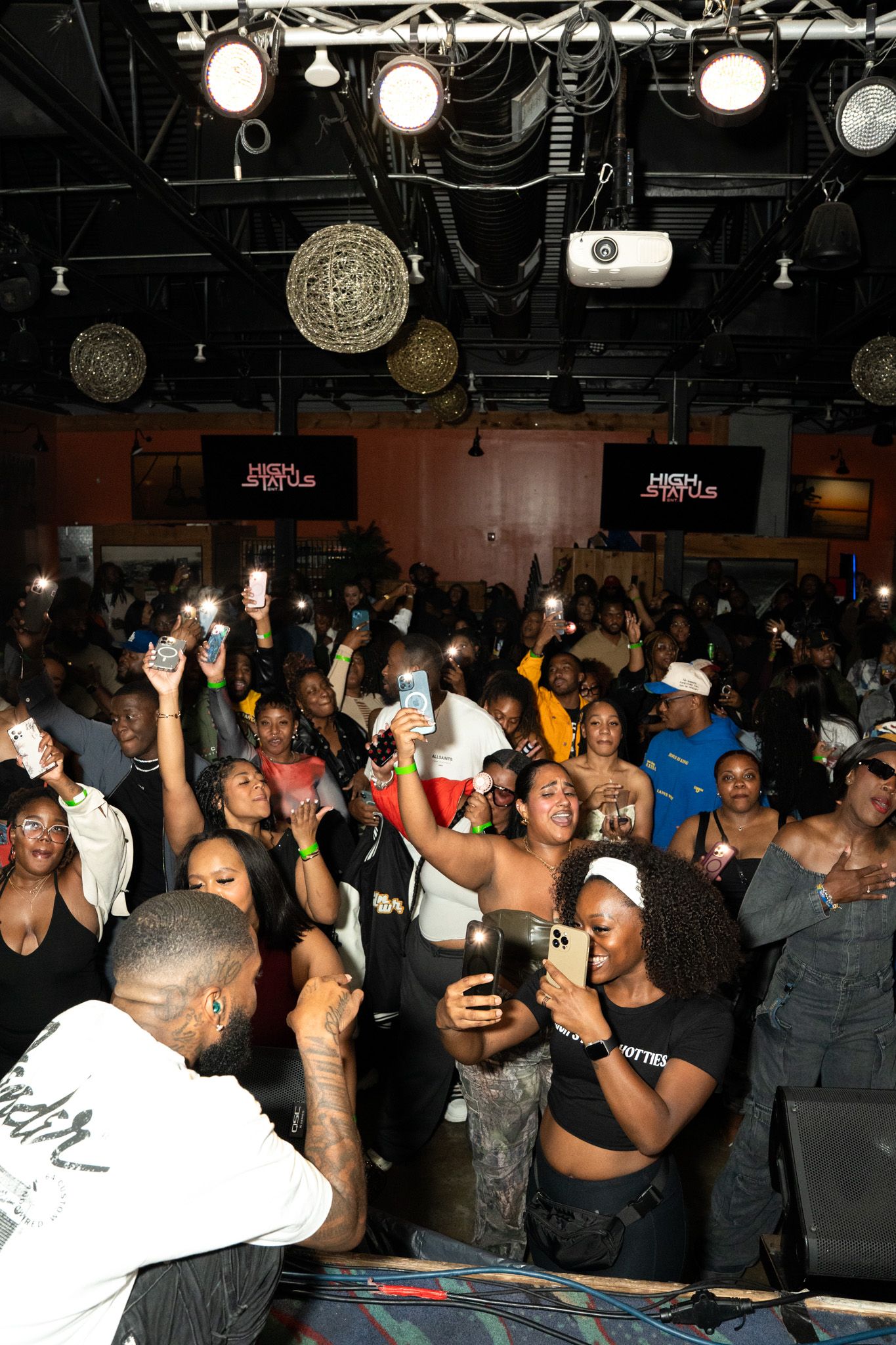 Crowded nightclub dance floor with people celebrating under overhead lighting.