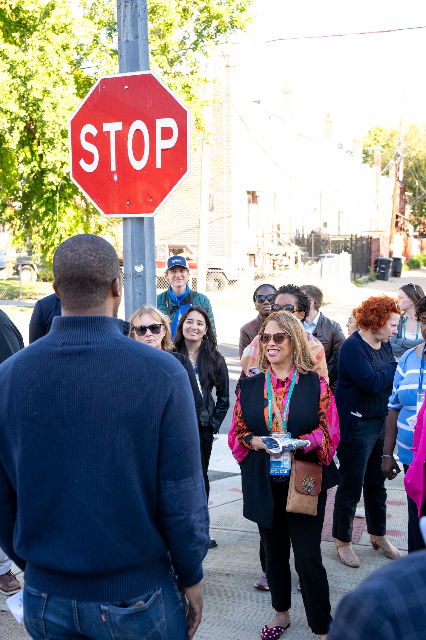 Group of people gathered near a stop sign for an outdoor business meeting.