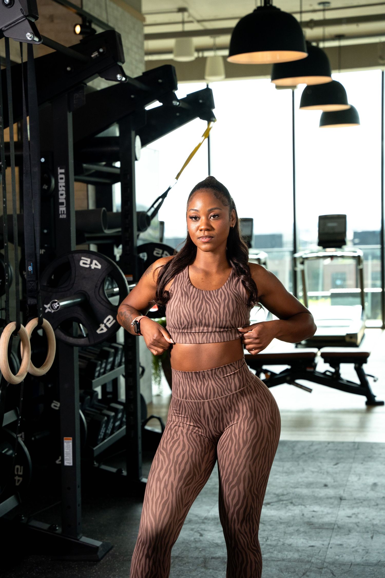 Workout session in modern gym with equipment and large windows.