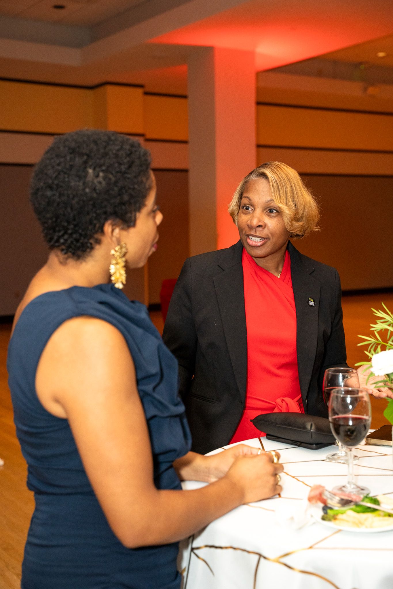 Two attendees engaged in conversation at an elegant dinner event with ambient lighting.