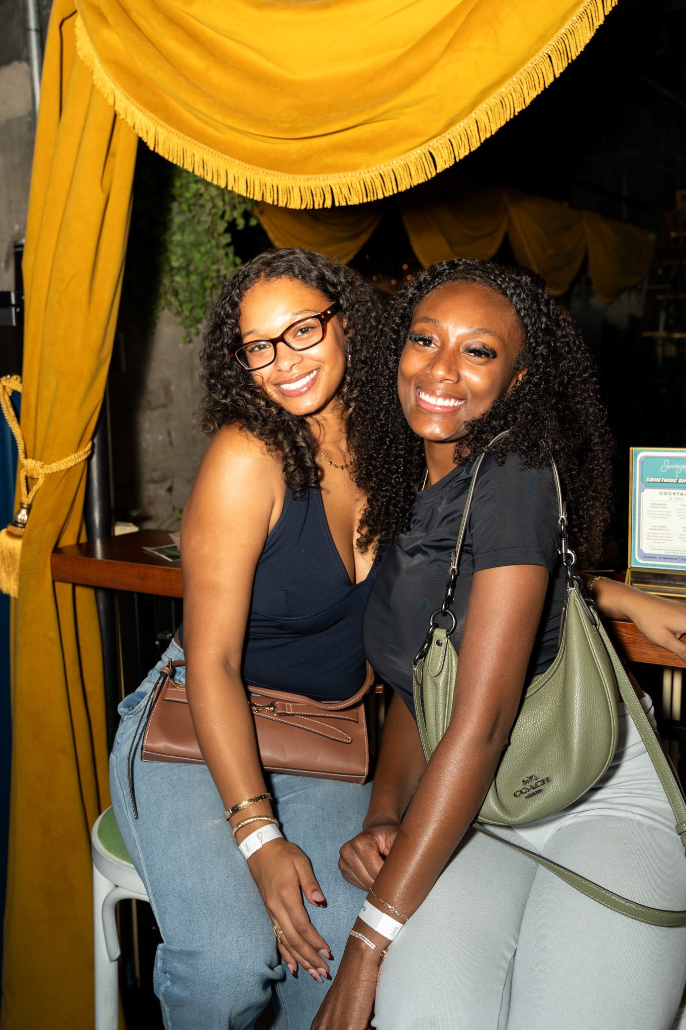 Friends posing together at a social gathering under yellow decor.