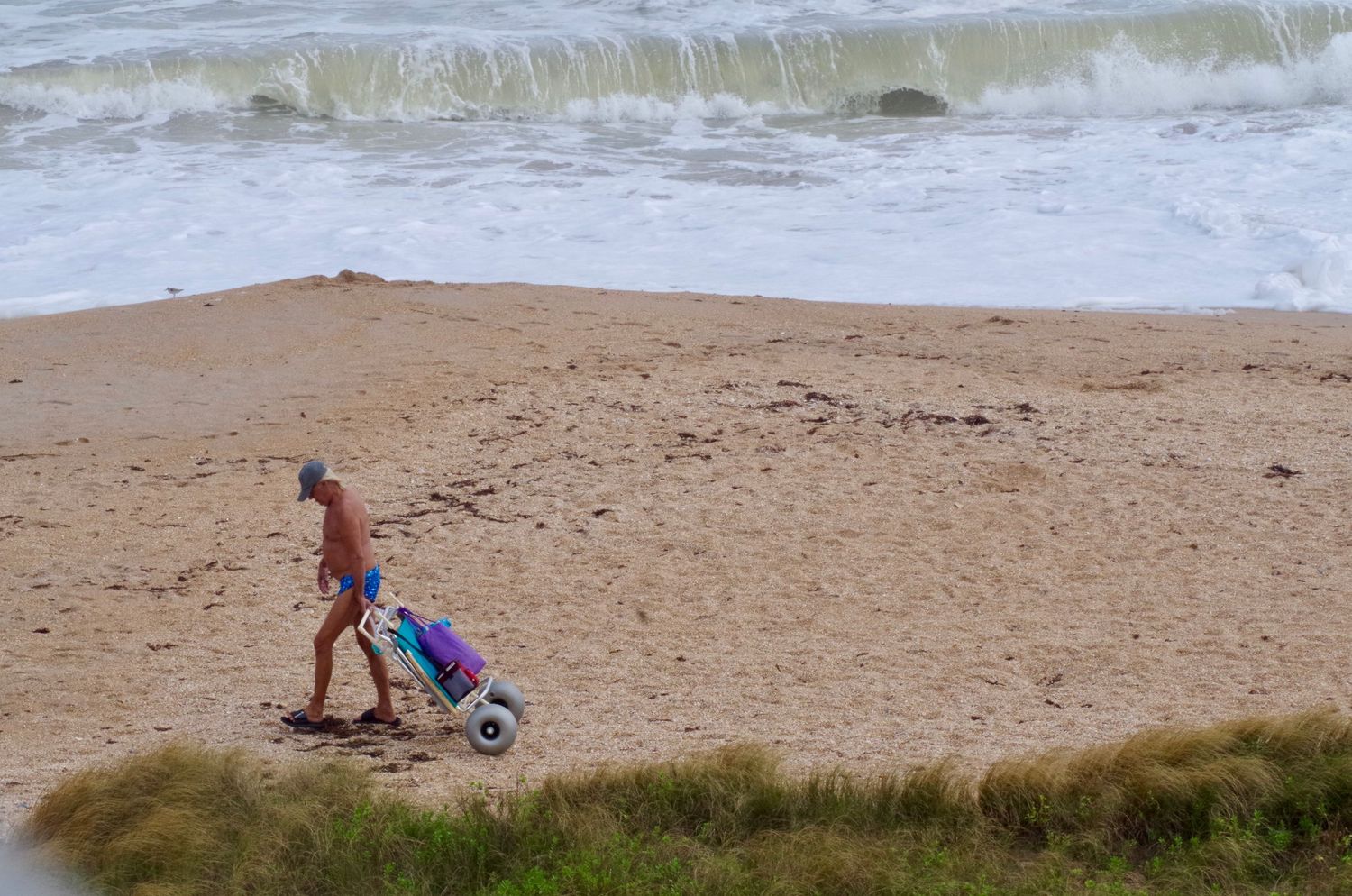 Candid photo of an old man walking peacefully on the beach, captured with a soft, warm, and distinctly nostalgic feel.