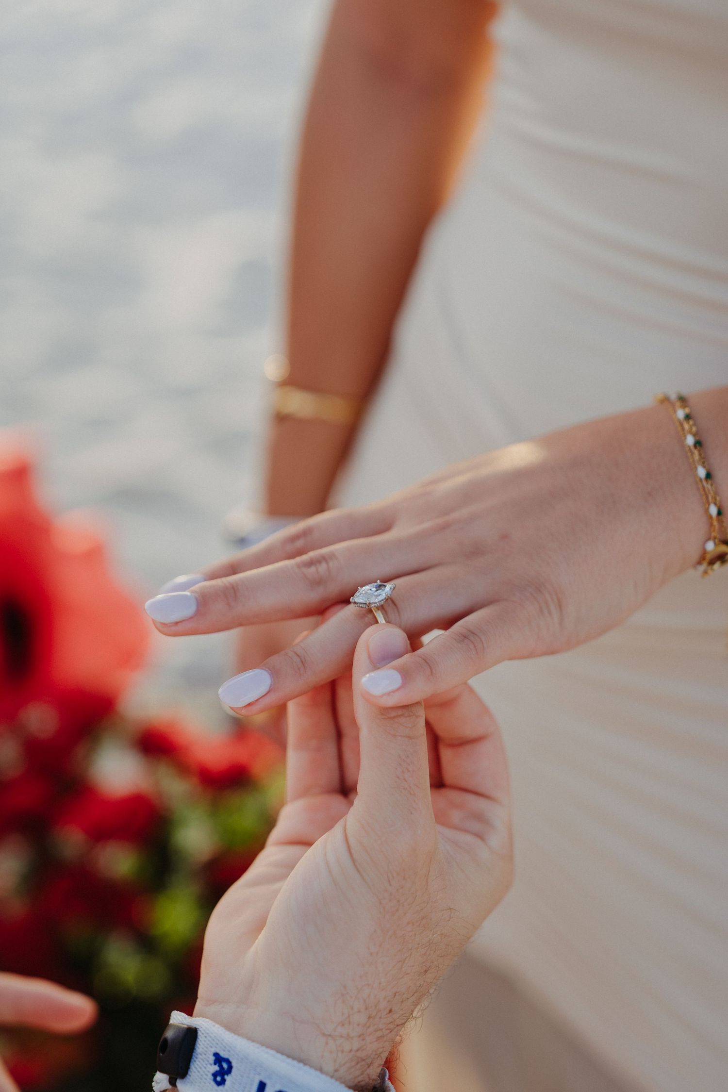 Close-up of a diamond engagement ring being placed on a womans finger.