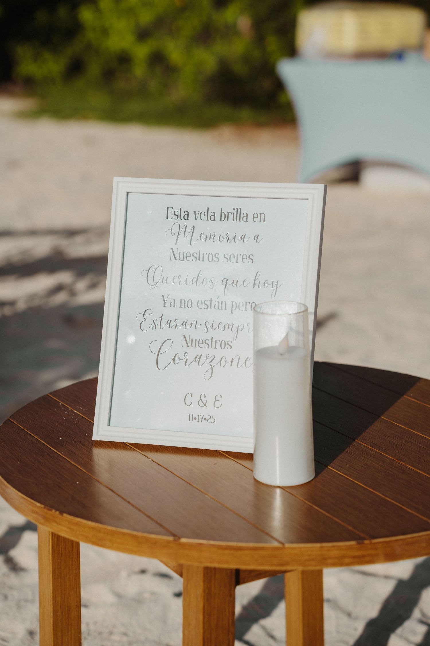 Spanish memorial candle sign on wooden table at an outdoor beach wedding ceremony.