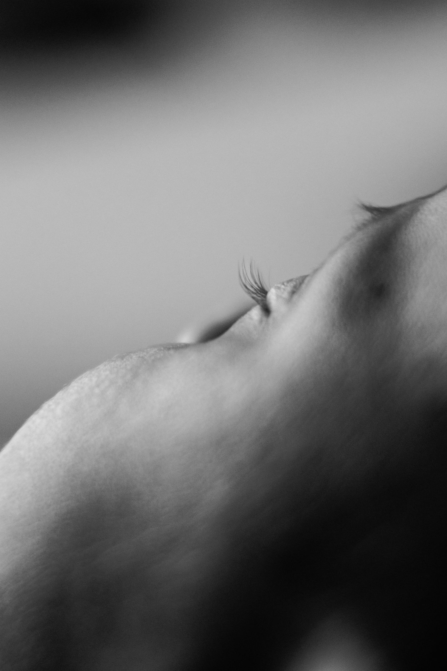 Extreme close-up black and white photo of a sleeping newborn baby's delicate eyelashes.