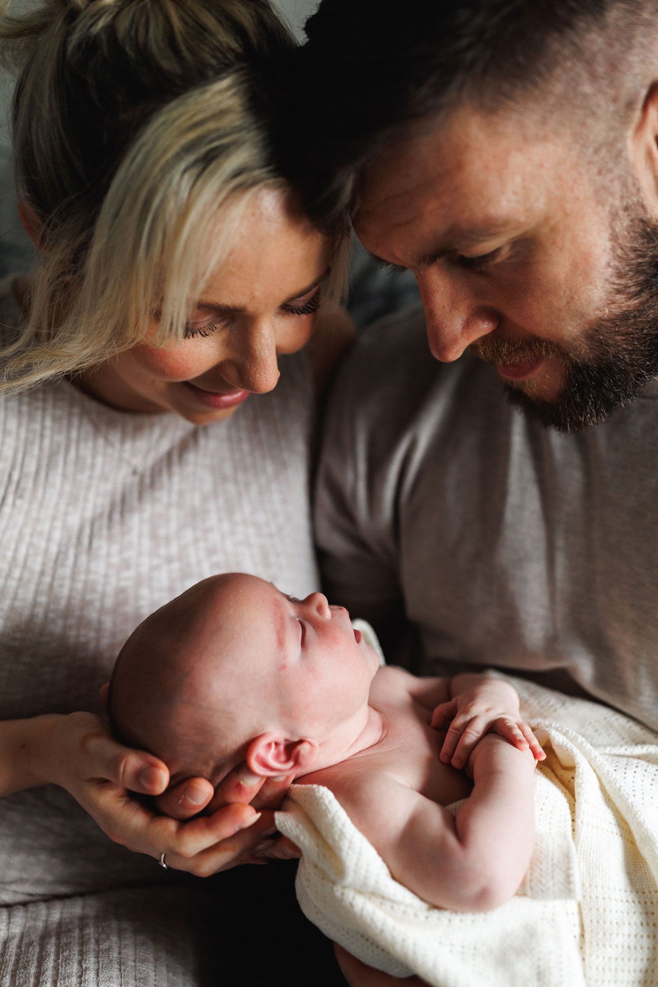 Family cuddling newborn Oliver during an at-home newborn photography session in Leicestershire