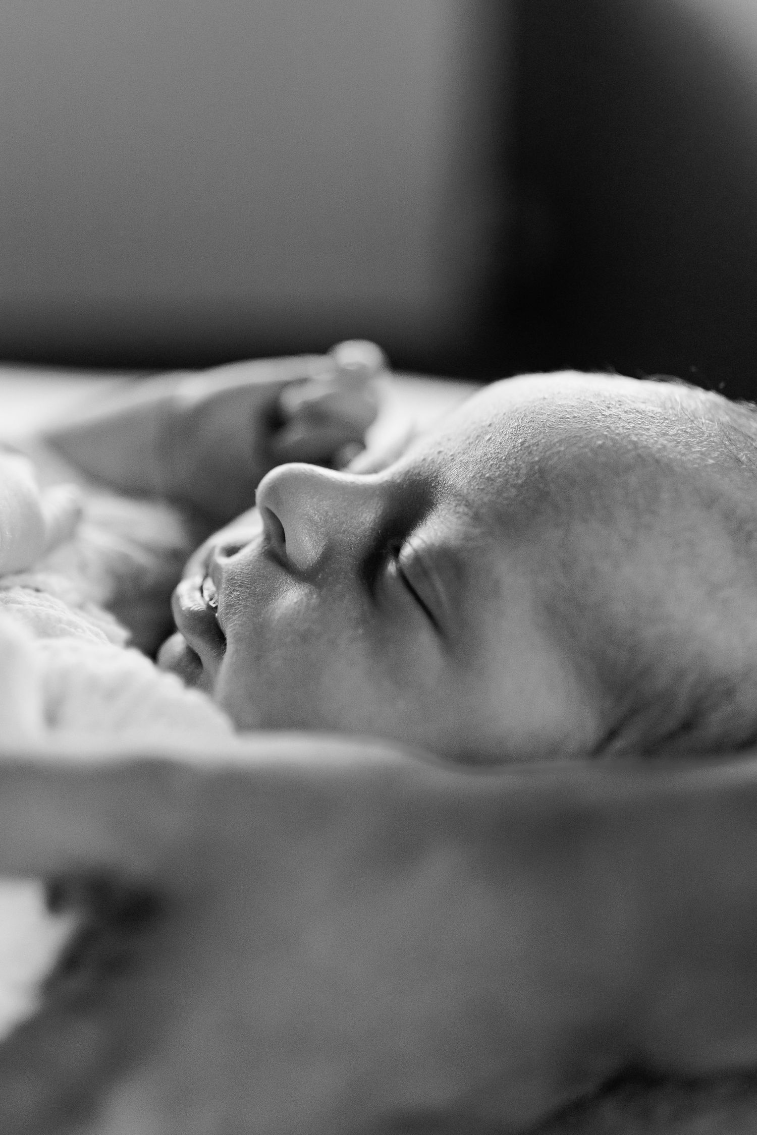 Black and white close-up profile of peaceful sleeping newborn baby face.
