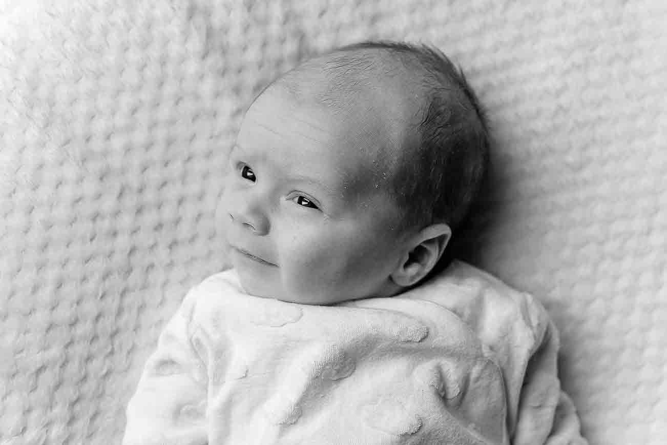 Awake newborn baby looking towards the camera during a natural lifestyle newborn photography session at home.