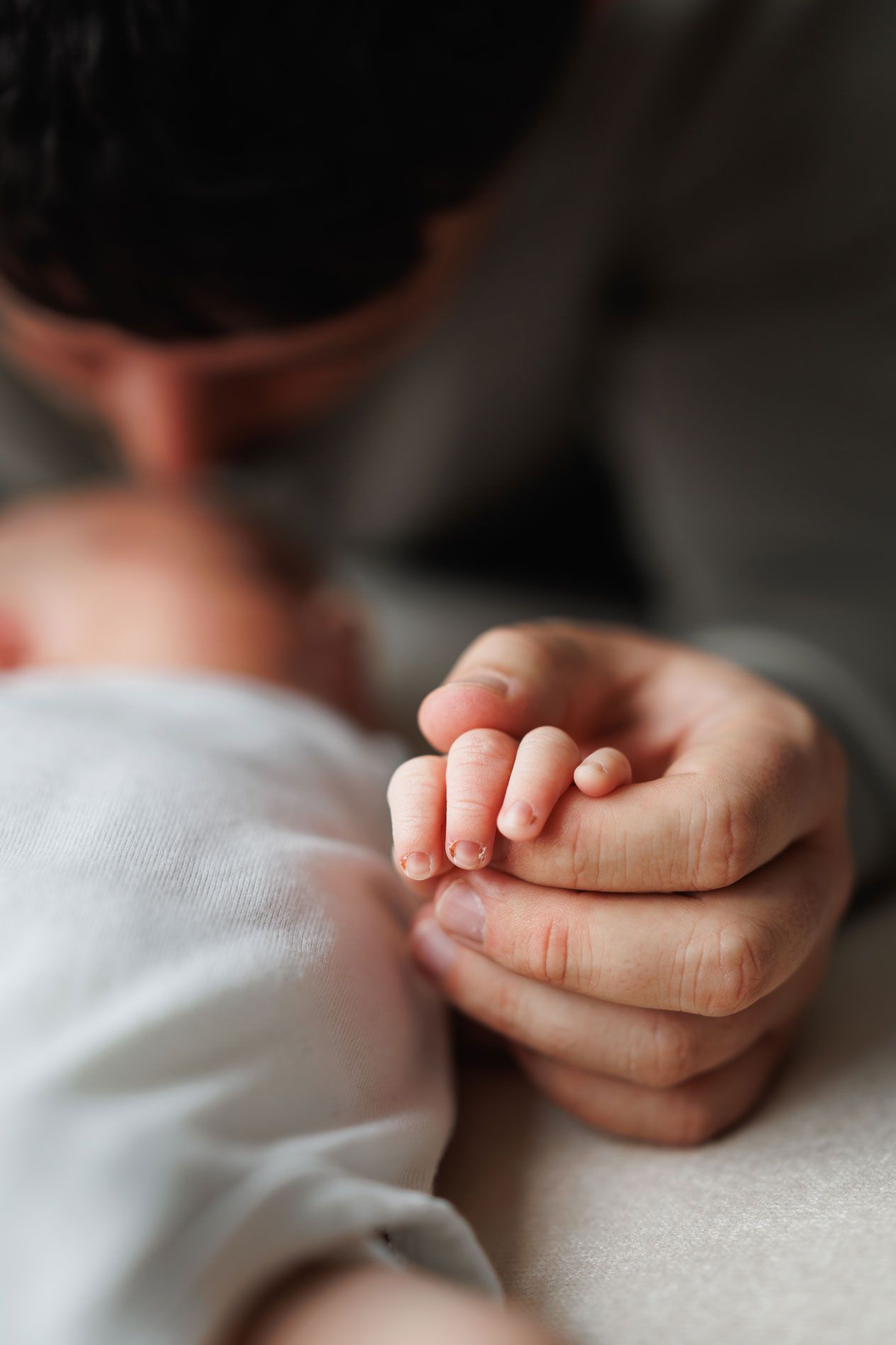 Father tenderly kisses his newborn baby's tiny hand while the infant rests peacefully.