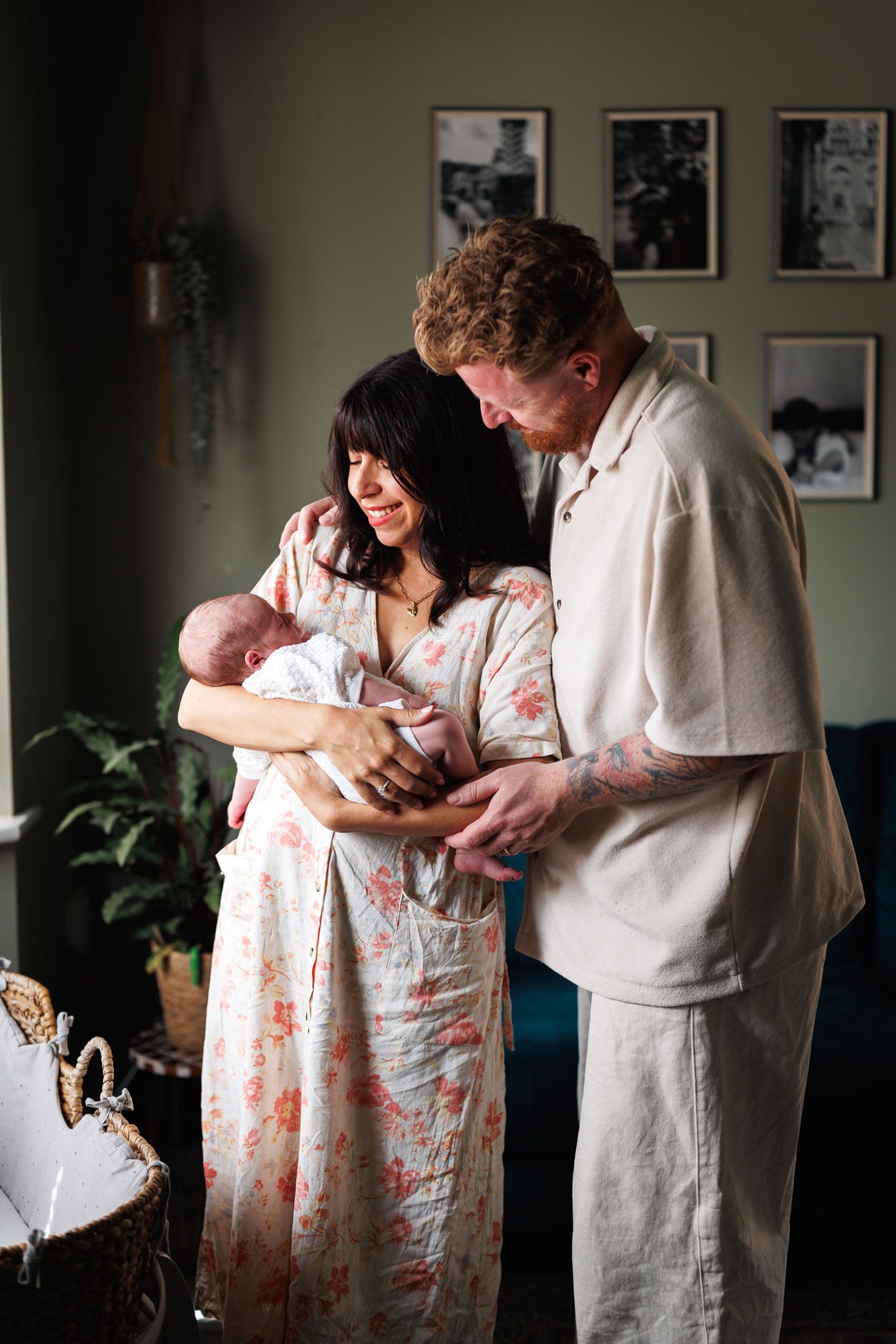 New parents gazing down at their newborn baby together in a cozy home setting.