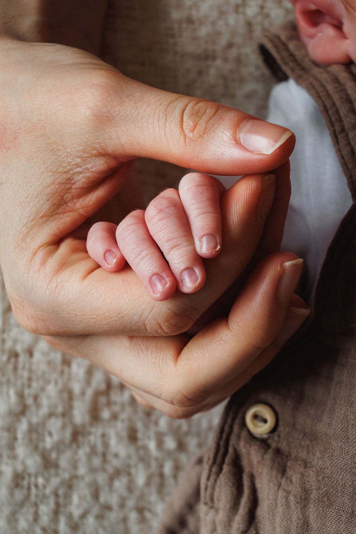 Close-up of a newborn baby's tiny hand gently gripping an adult's finger, symbolizing new life and parental bond in their Nottingham Newborn