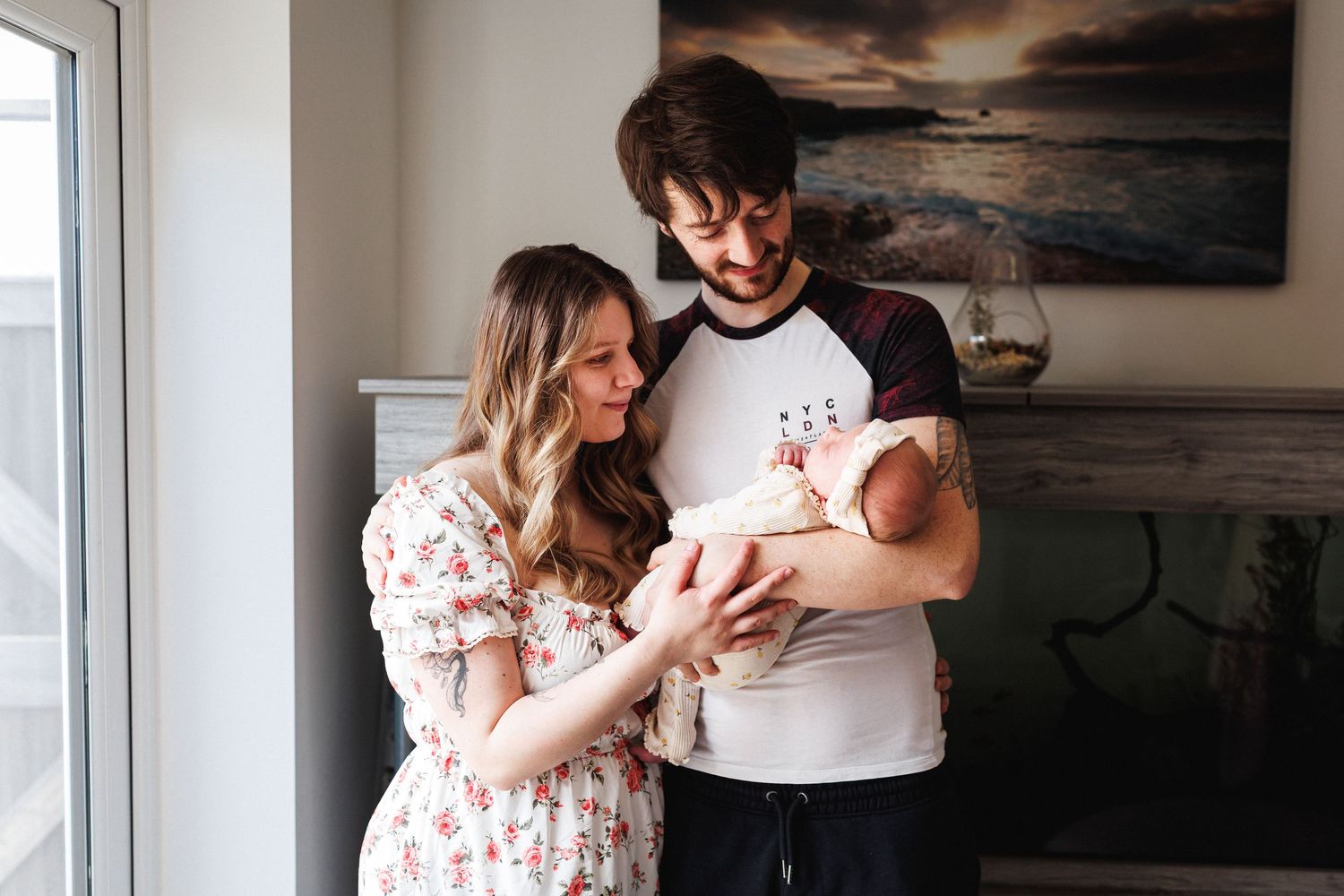 Happy couple in a cozy home interior tenderly cradling their newborn baby together.