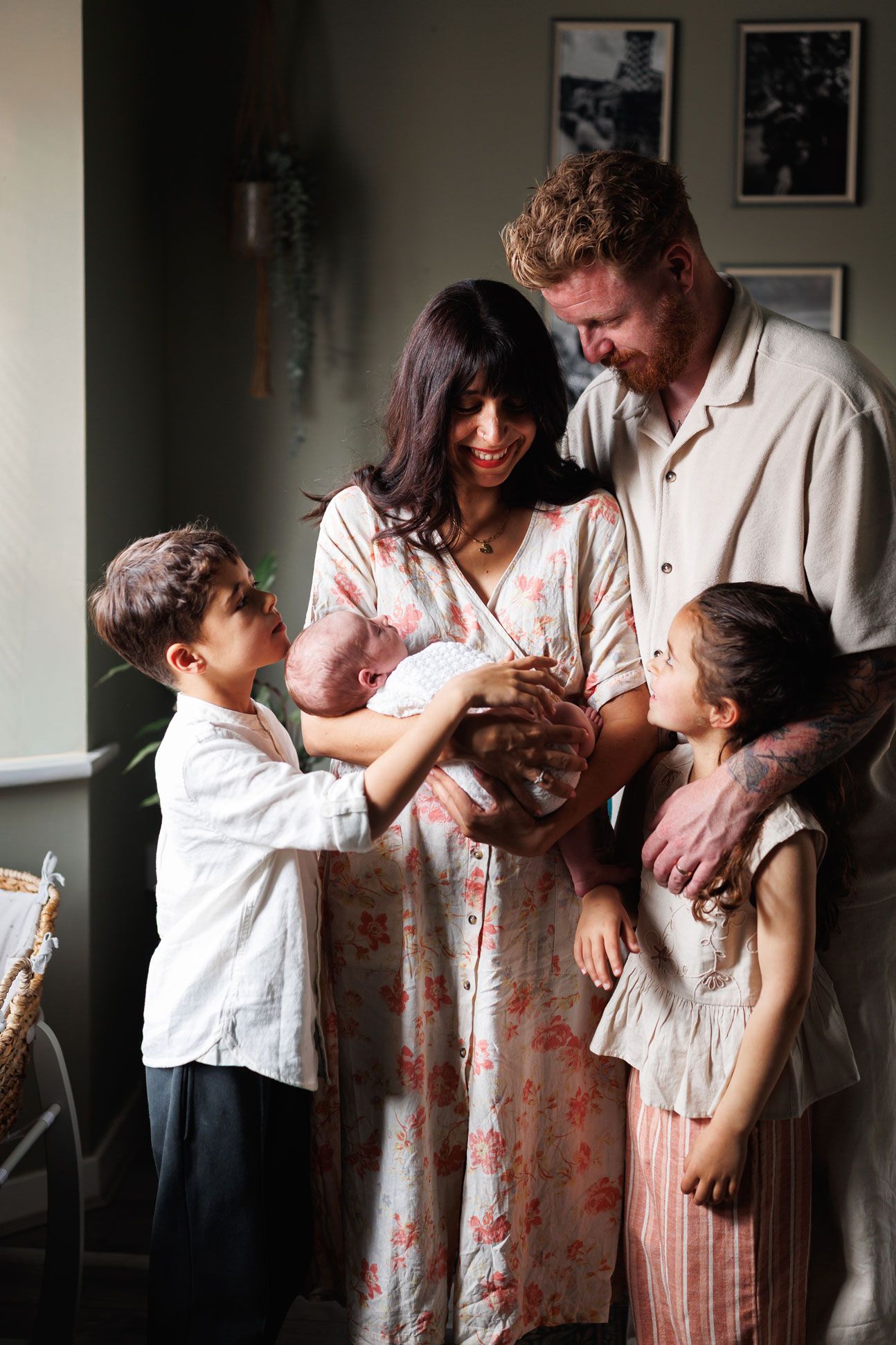 Smiling family with two children and parents lovingly holding their newborn baby at home.