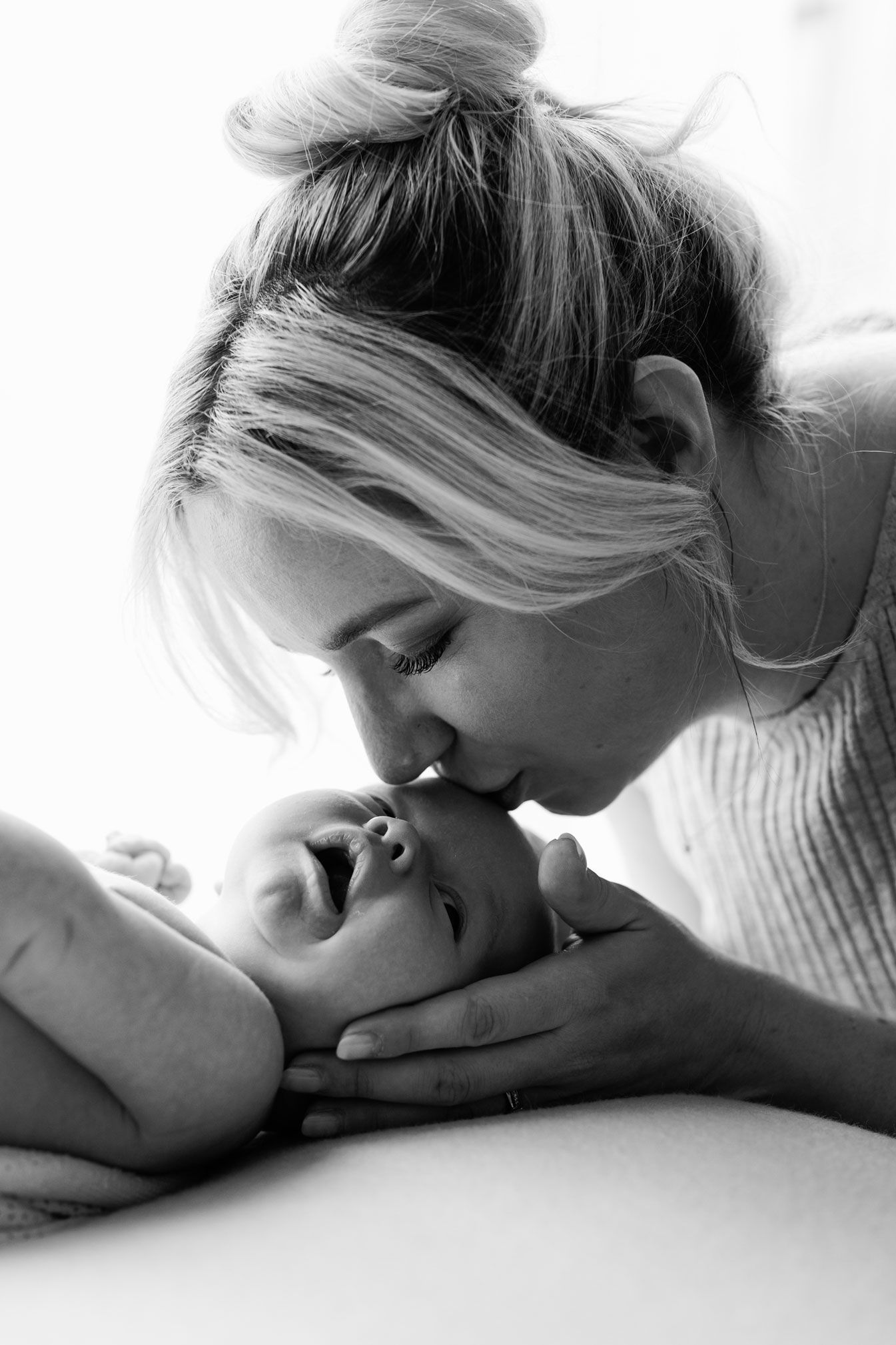 Mum cuddling her newborn baby during a relaxed lifestyle session at home