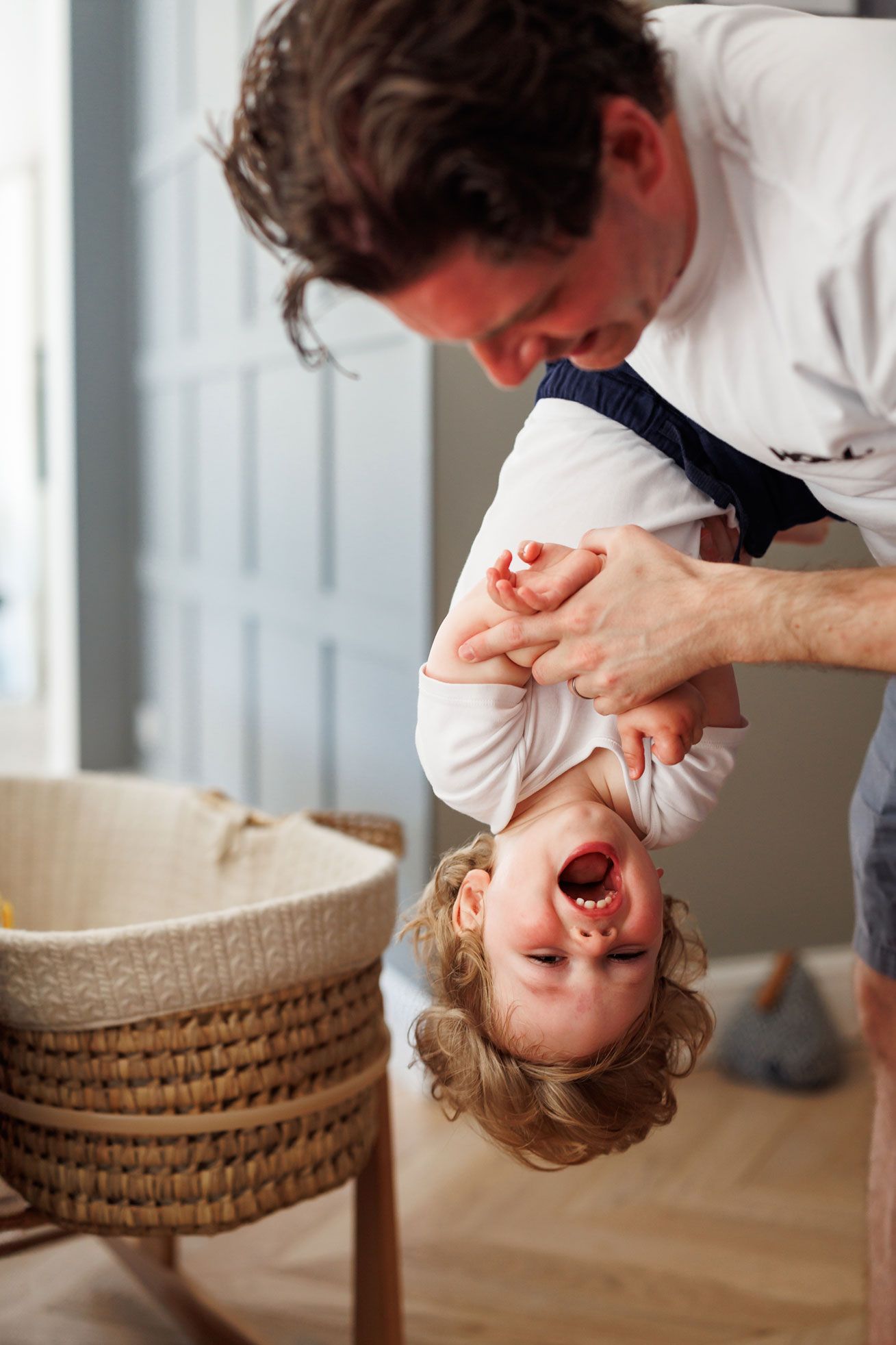 Parent playing with an older sibling during a relaxed family-focused at-home newborn photography session.