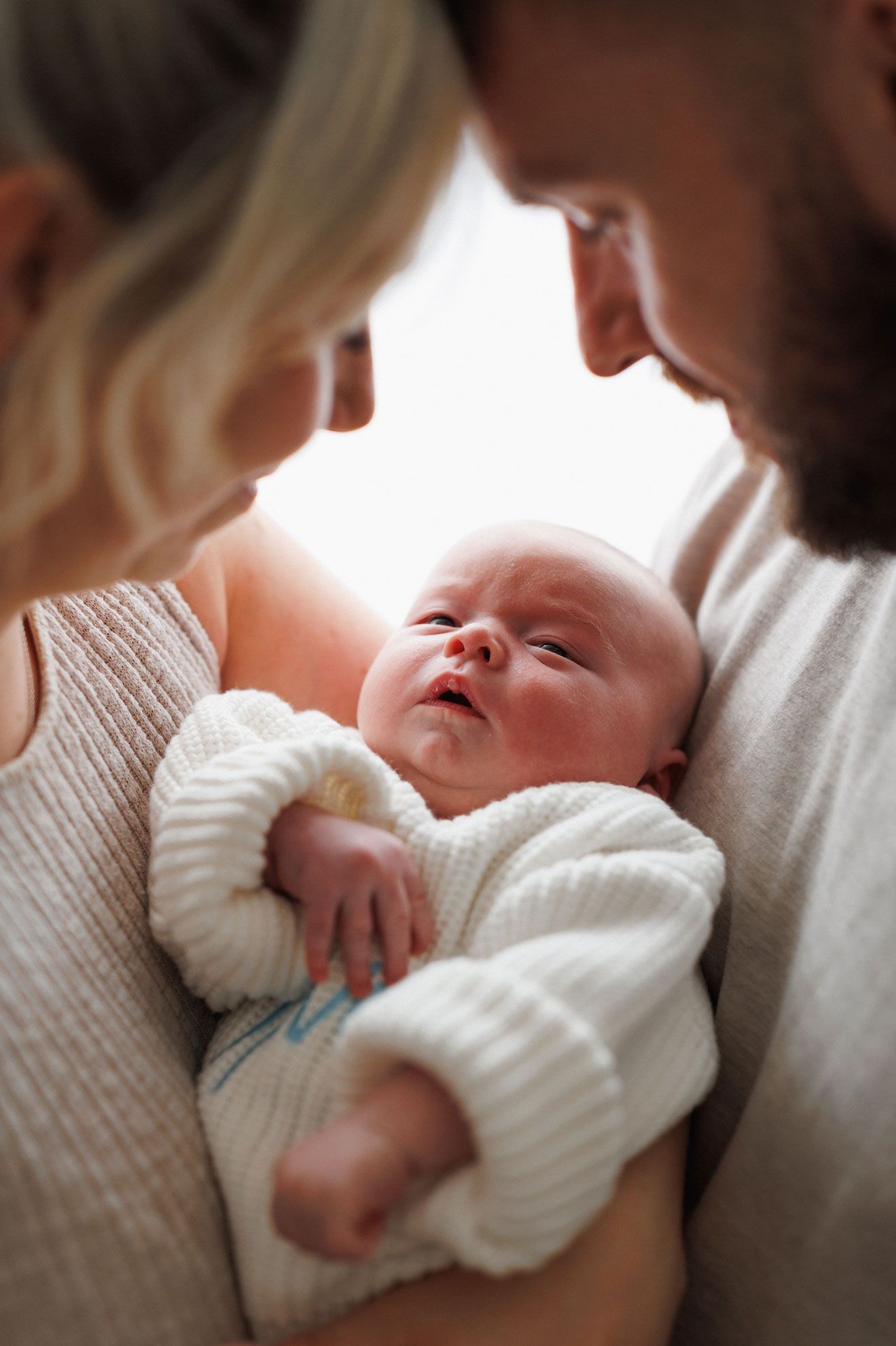 Family cuddling newborn Oliver during an at-home newborn photography session in Leicestershire