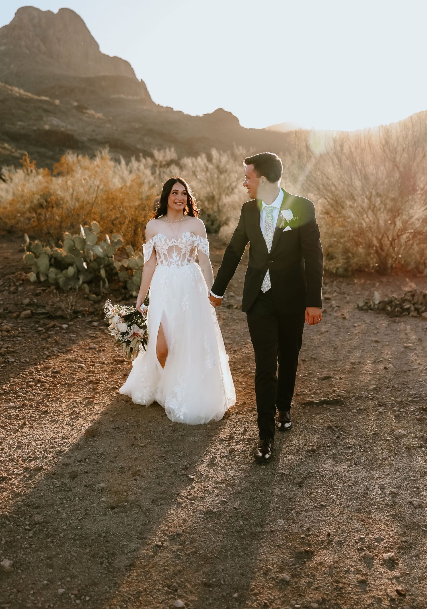 Bride and groom holding hands under Arizona desert sunset, candid wedding photography