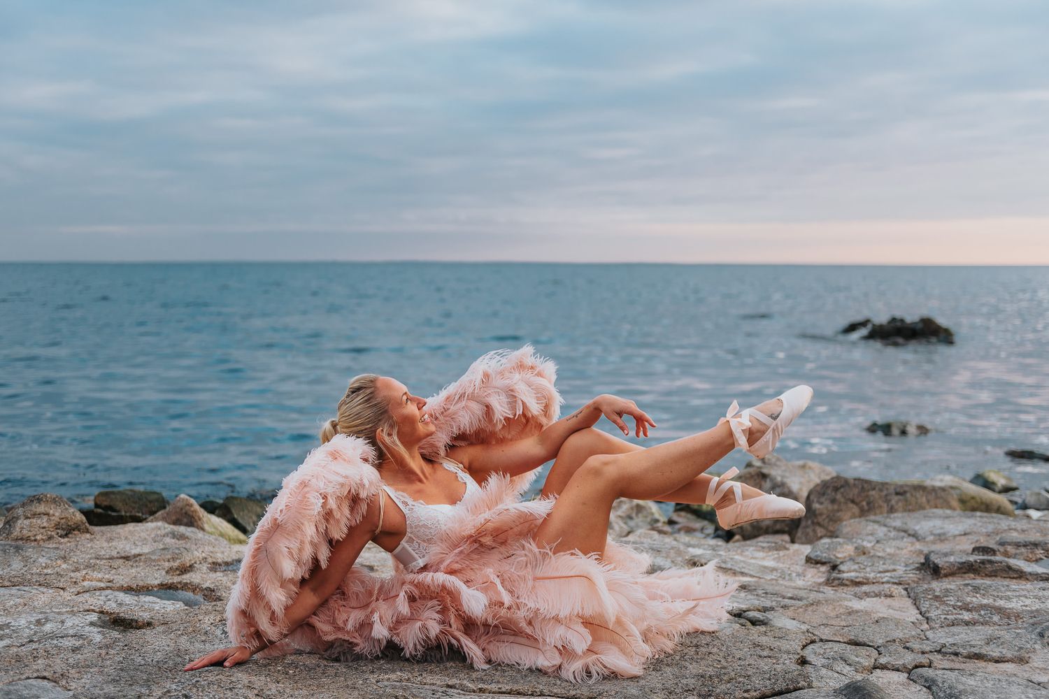 Boudoirfotografering utomhus nere vid havet med änglavingar