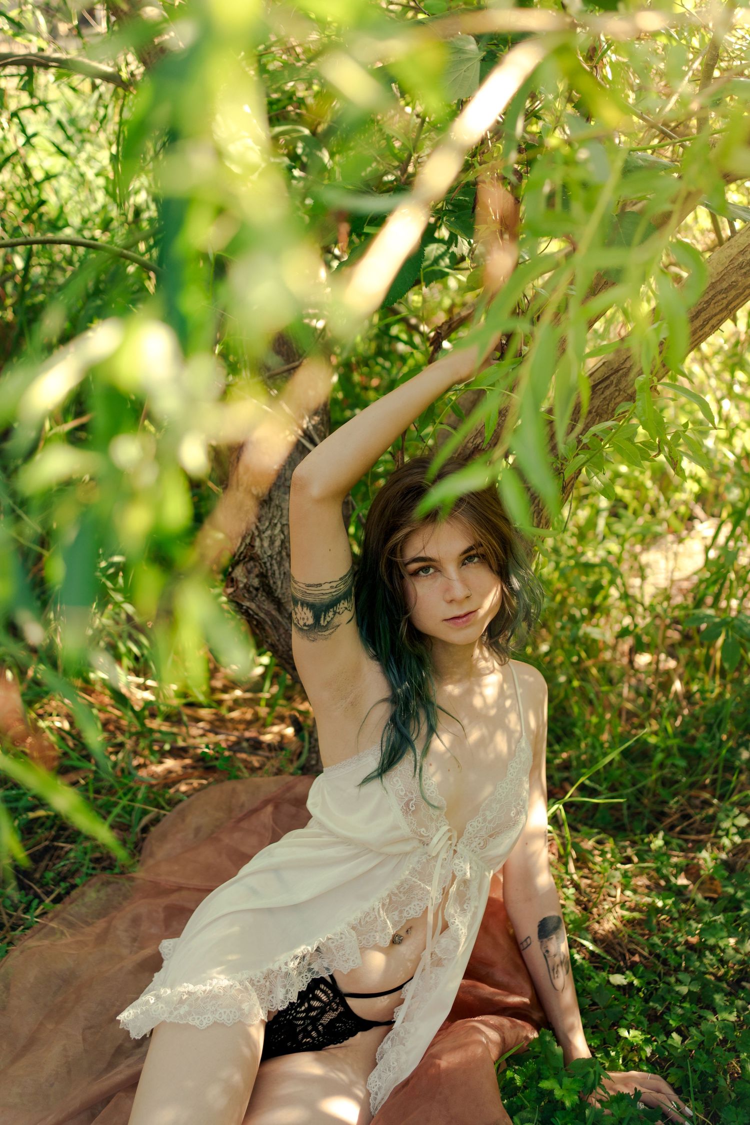 Ethereal garden portrait with white dress and dappled sunlight through leaves.