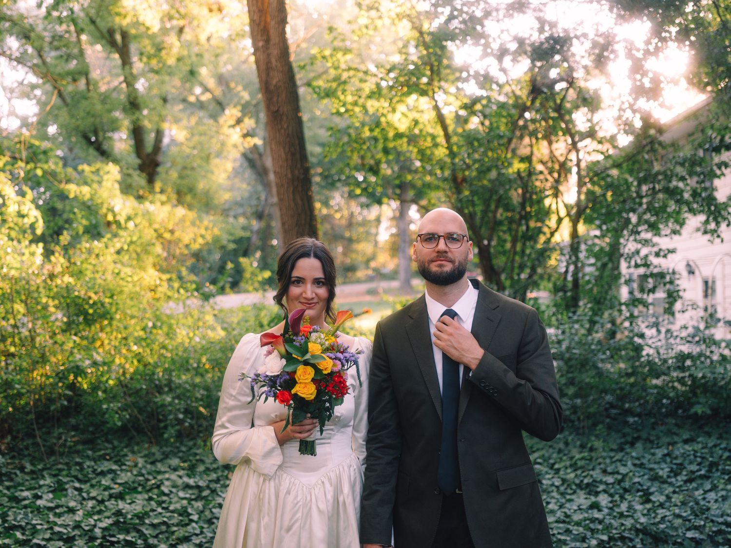 Newlywed couple posing in a lush garden setting with sunflowers.