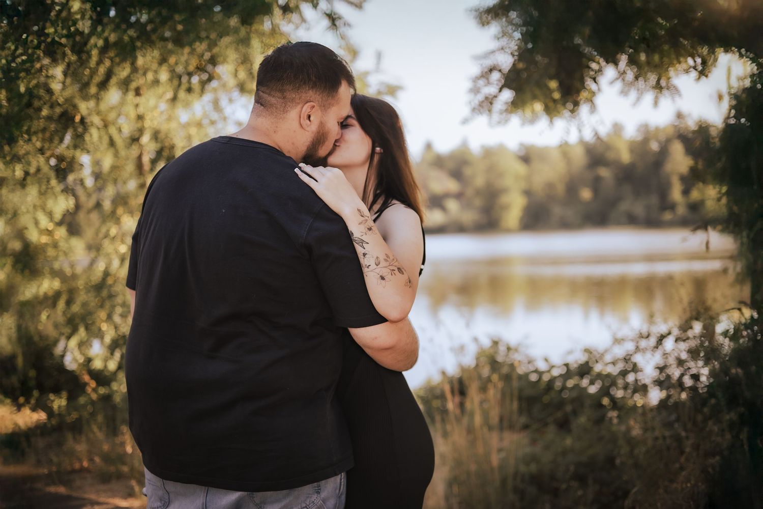 An intimate embrace captured against a serene lake backdrop during sunset.