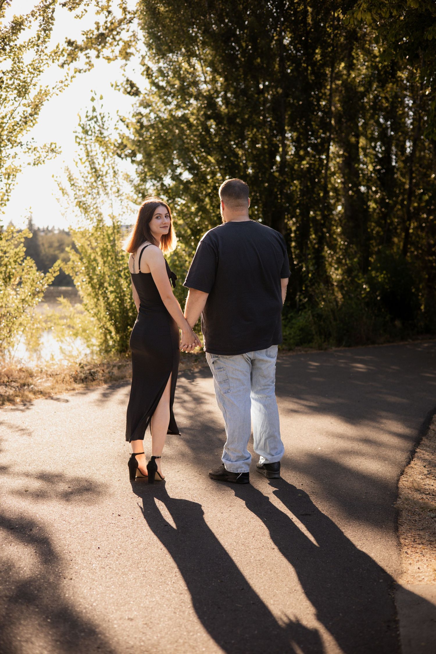 A couple walking together on a path at sunset casting long shadows in a romantic outdoor setting.