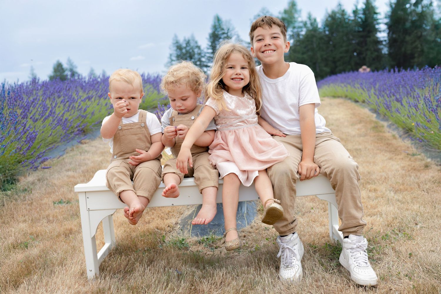 A group sits together on a white bench in a blooming lavender field.
