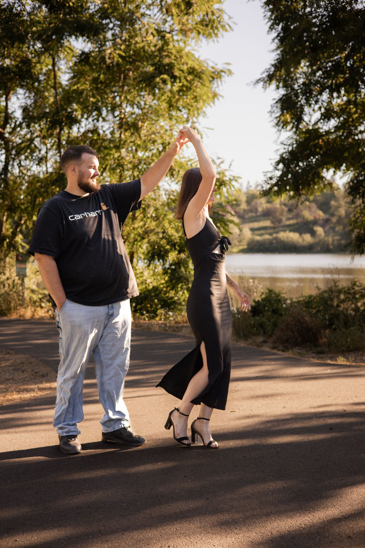 A playful dancing moment captured on a path by a lake during golden hour.
