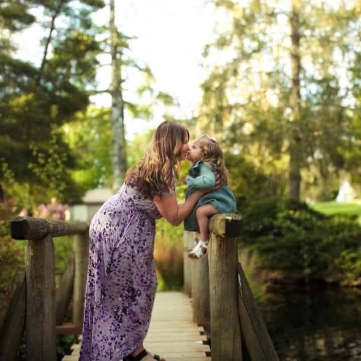 A sweet interaction captured on a rustic wooden bridge surrounded by greenery.