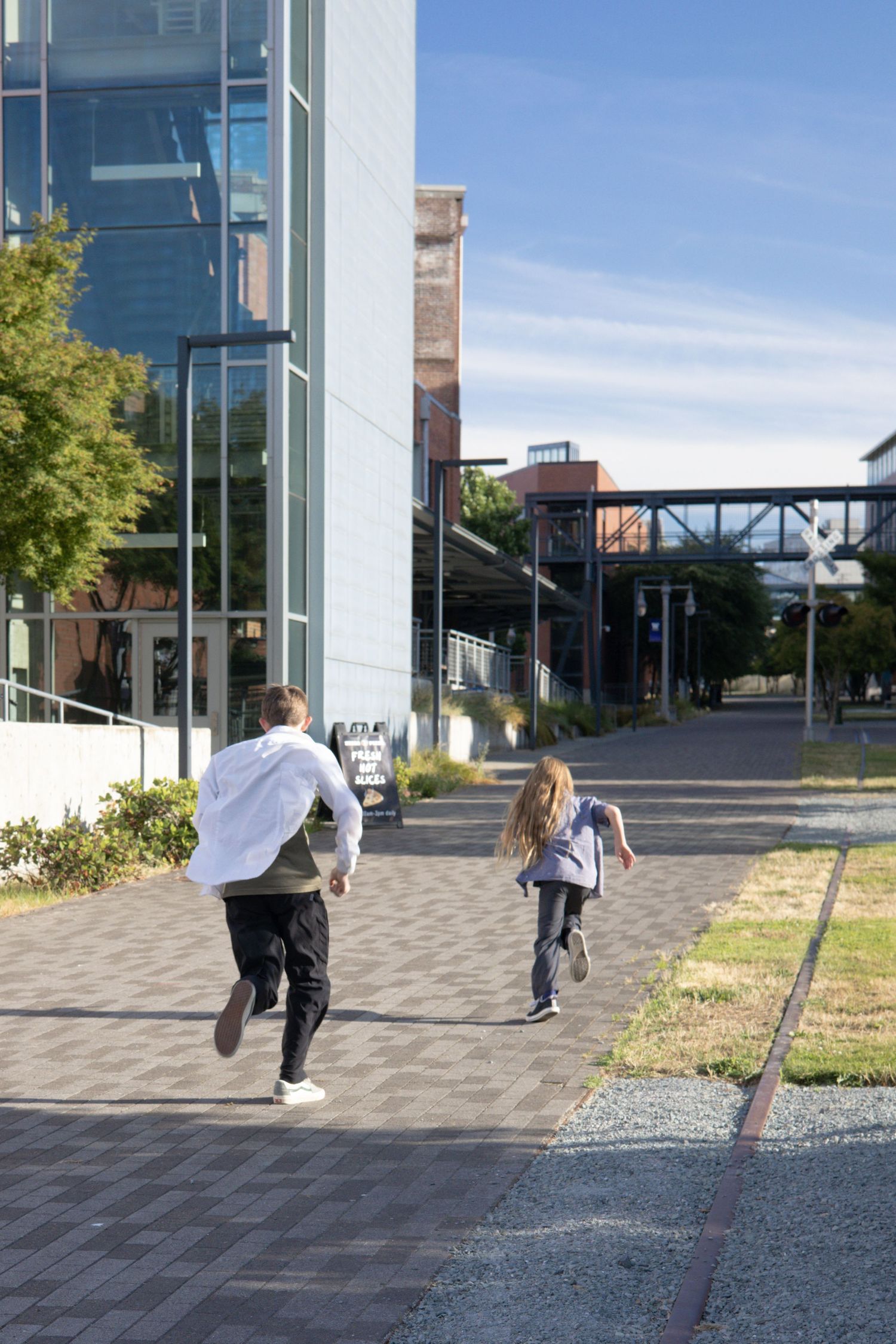 People running on a paved path between modern office buildings.