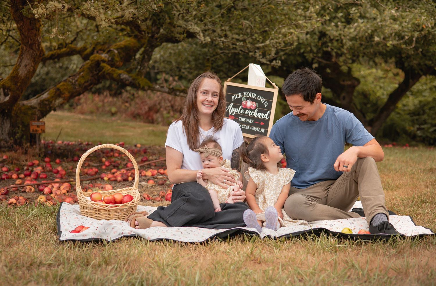 A couple lying on a picnic blanket in a park studying together with textbooks and papers spread out.
