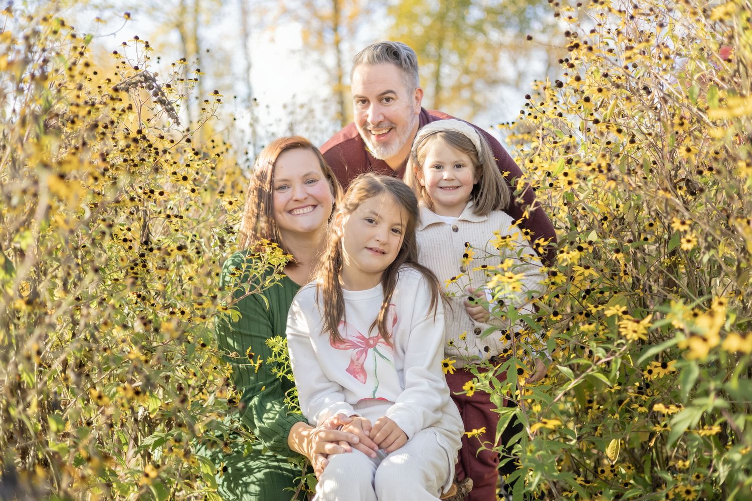 A group poses together outdoors during autumn with golden leaves in the background.