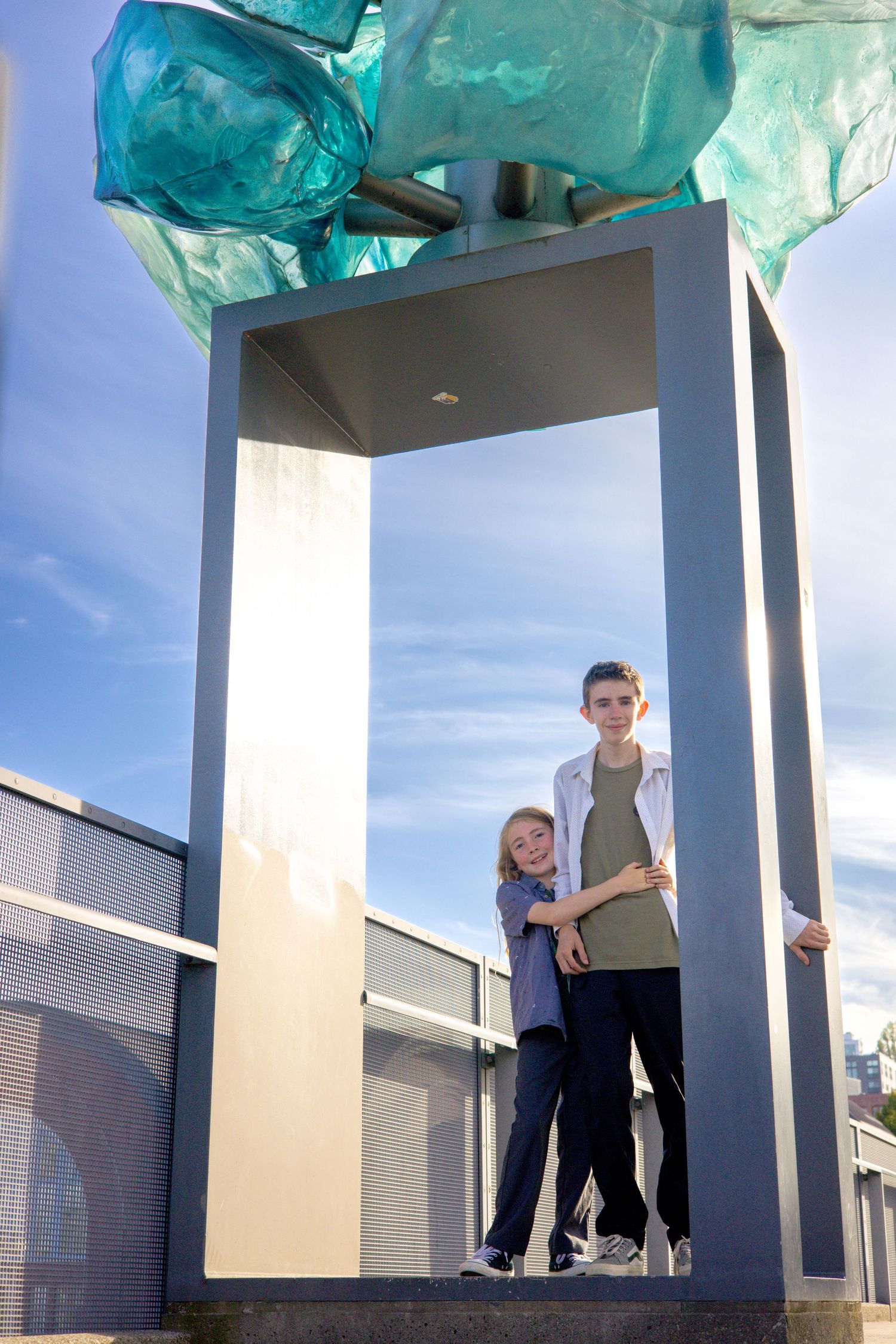 Modern architectural structure with turquoise glass elements against blue sky.