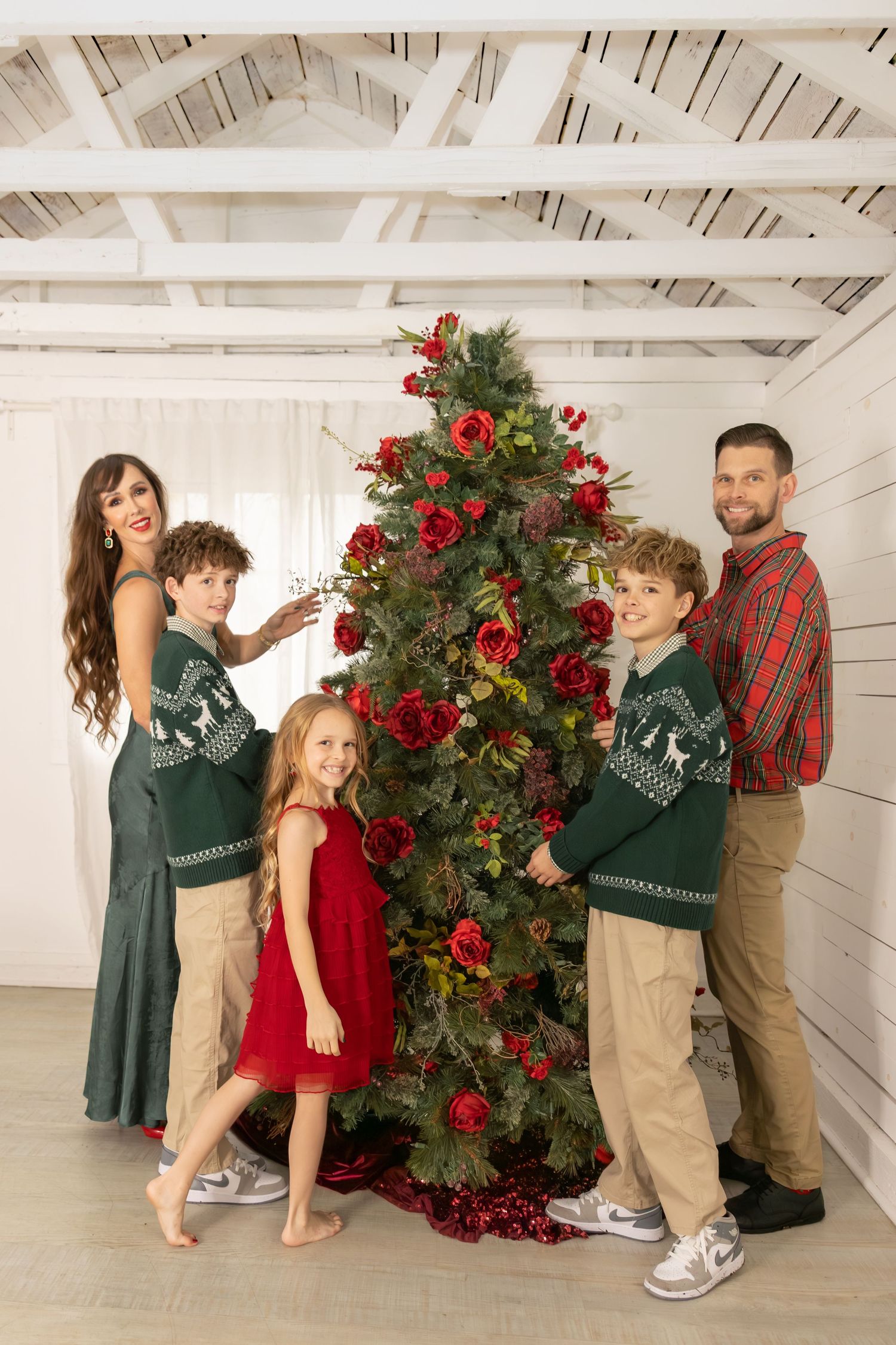 A group in red and green holiday outfits poses in a sequence of playful moments near a decorated Christmas tree.