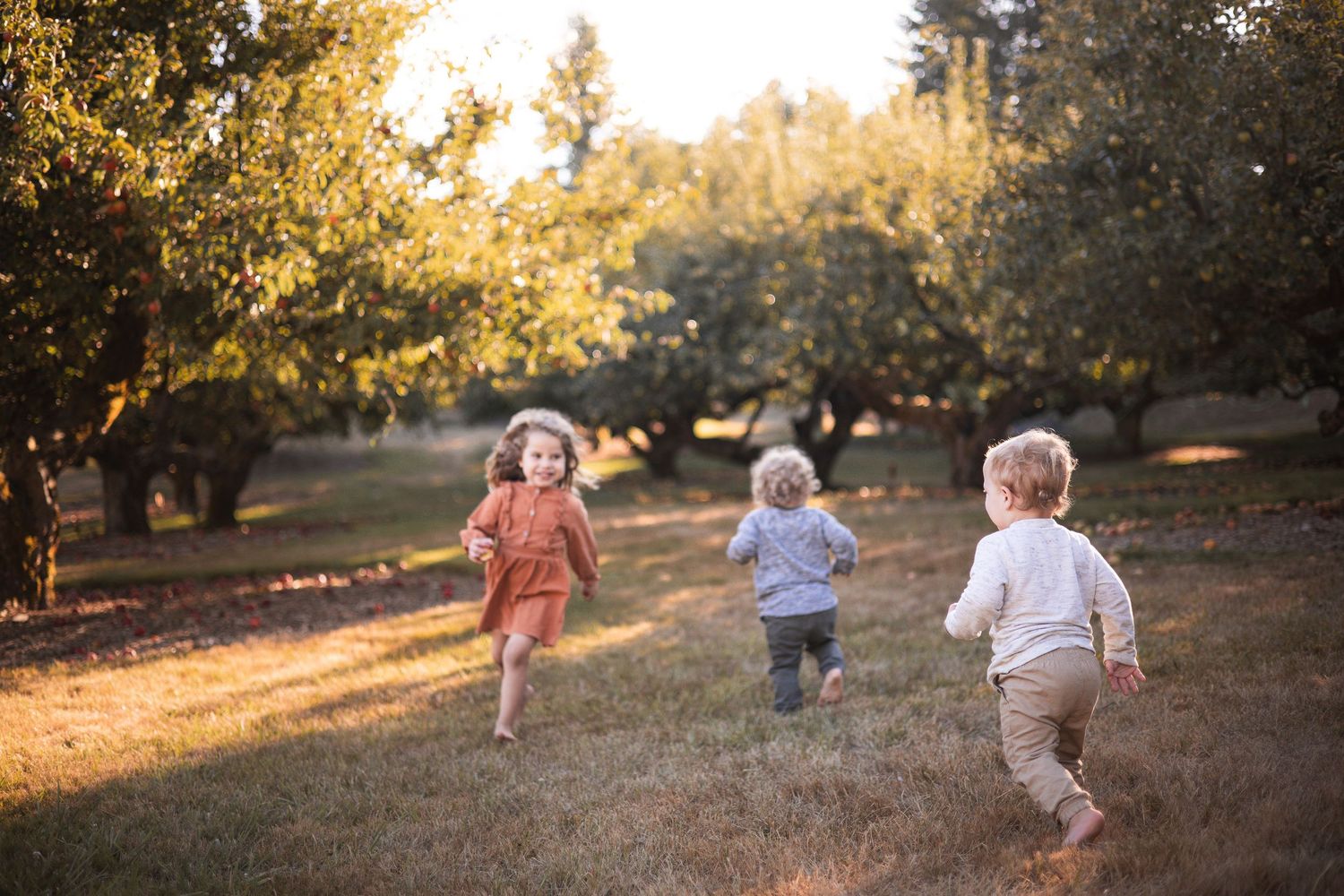 Children running and playing together in a sunlit park during golden hour.