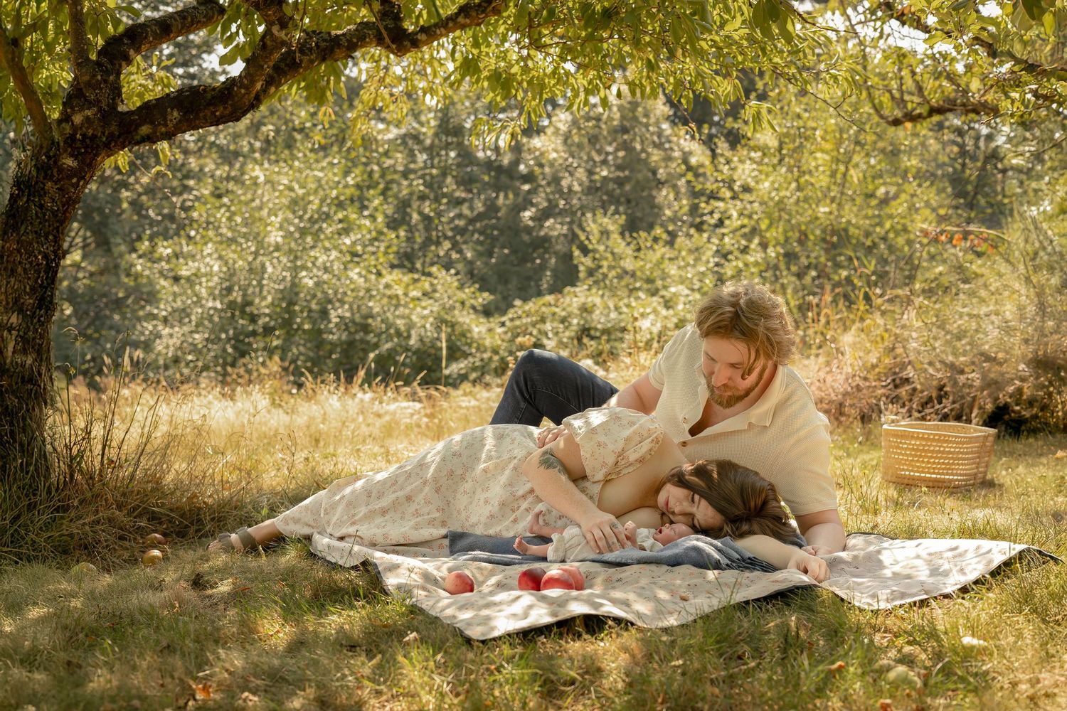 Couple with newborn on blanket in backyard apple orchard — romantic, cinematic lifestyle photography in Tacoma, PNW, South Sound WA