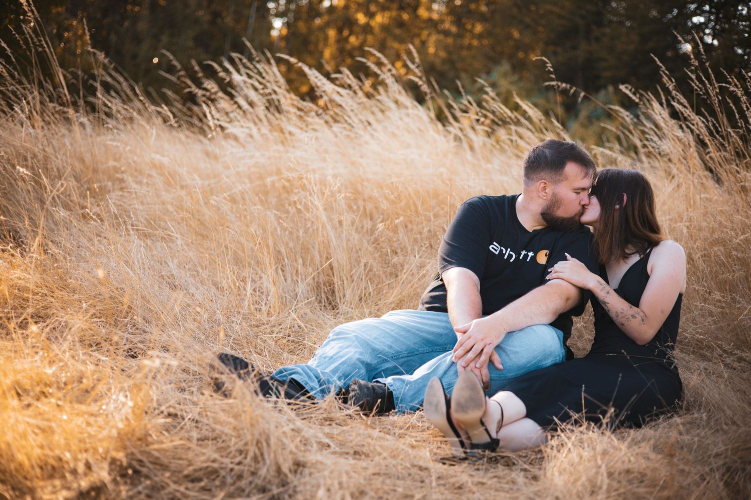 Couple lounging in golden grass during sunset photo session.