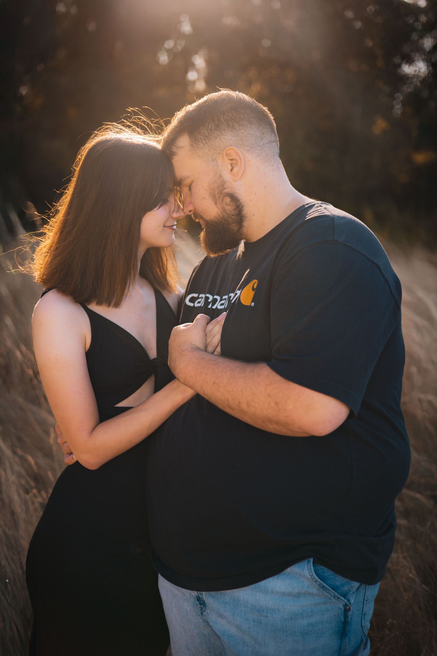 Romantic sunset photoshoot with couple embracing in golden light.