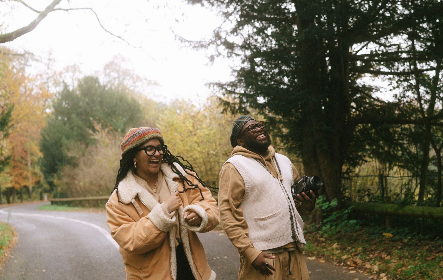Two friends in matching tan outfits enjoying a conversation on an autumn path.