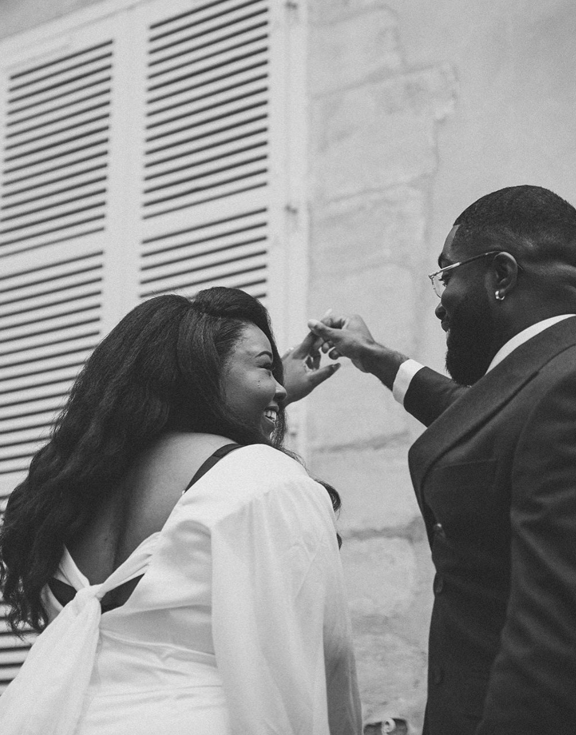 A candid moment between newlyweds showing joy and laughter against architectural details.