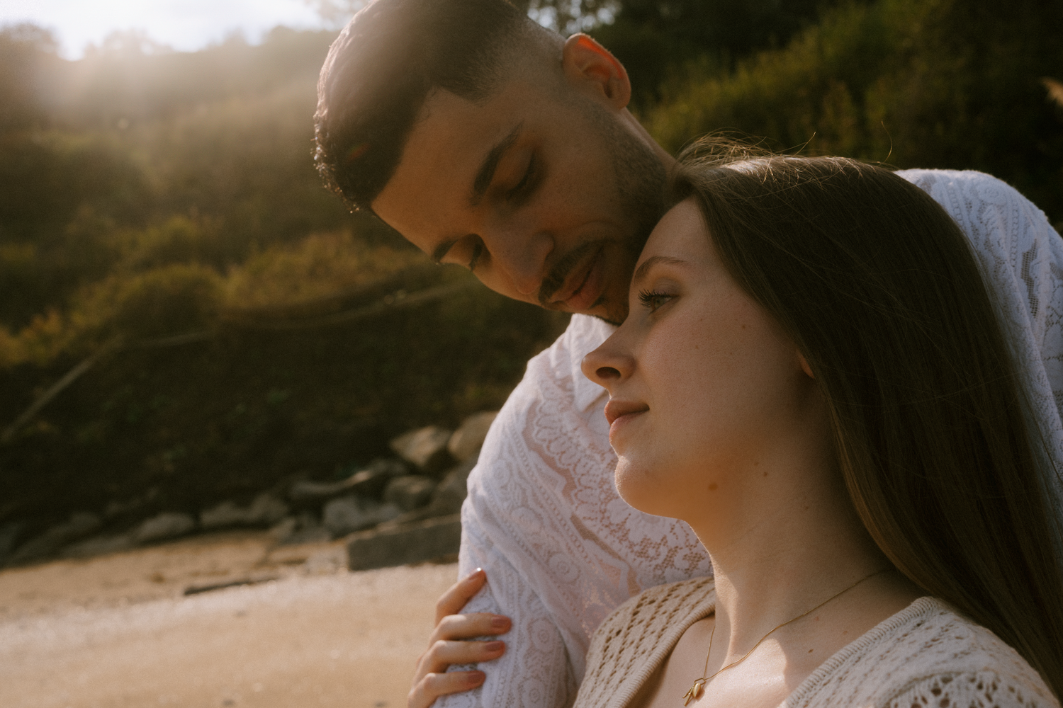 Intimate couple sharing a tender moment on beach at golden hour.