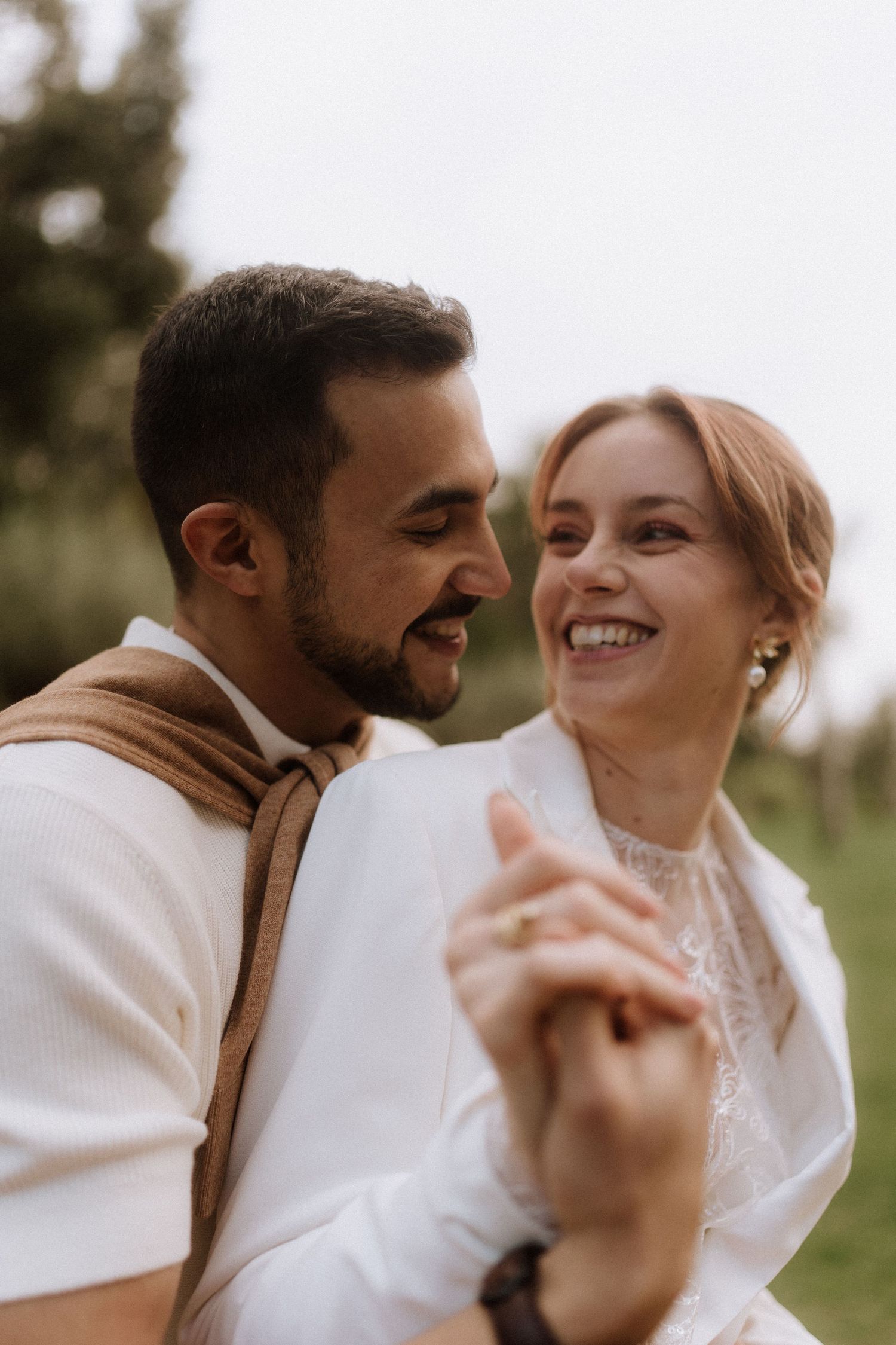 A joyful couple sharing an intimate moment outdoors while wearing light colored clothing.