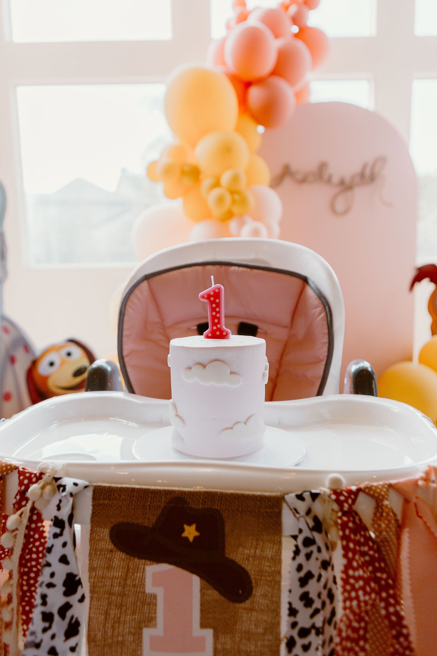 First birthday party setup with balloon arch and cowboy themed high chair decoration.