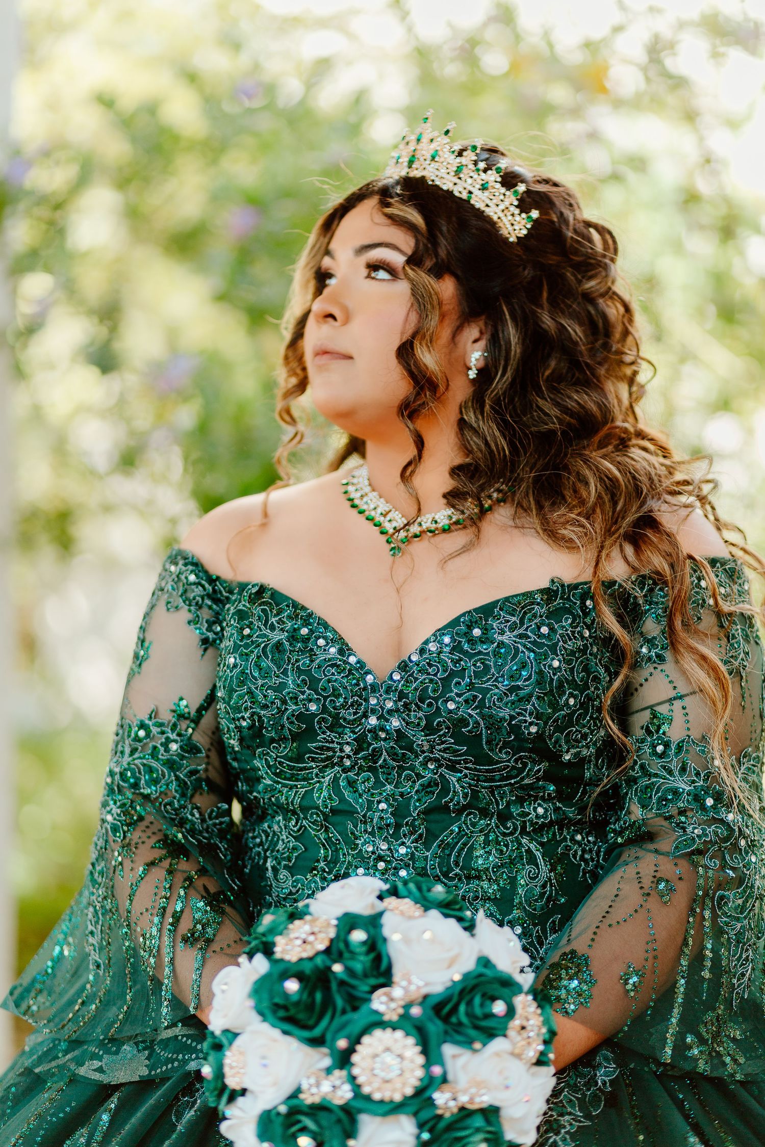 Stunning emerald green beaded gown with matching bouquet photographed in garden setting.